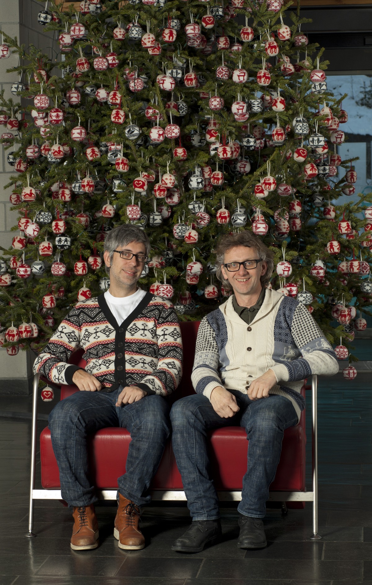 Maihaugens juletre 2015, pyntet med strikkede julekuler av Arne og Carlos. Her sitter de foran treet. Foto: Camilla Damgård.